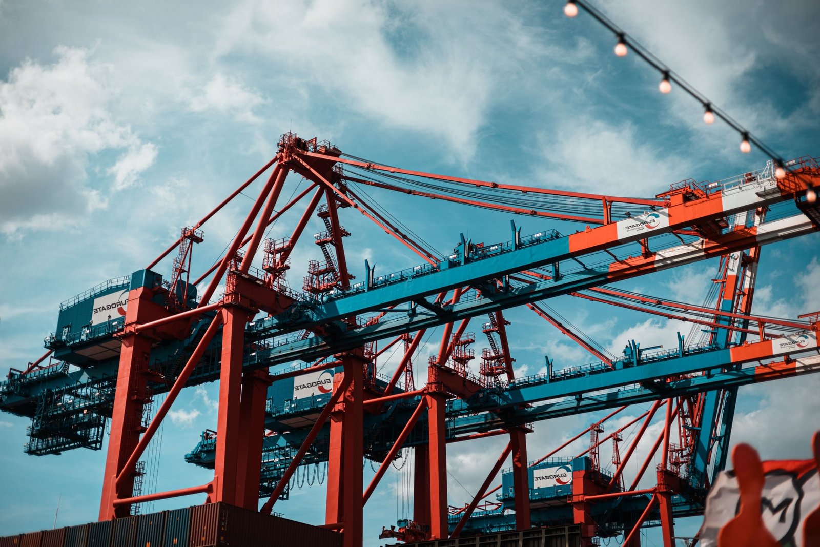 Dynamic view of industrial cranes at Hamburg port with a vibrant sky backdrop.