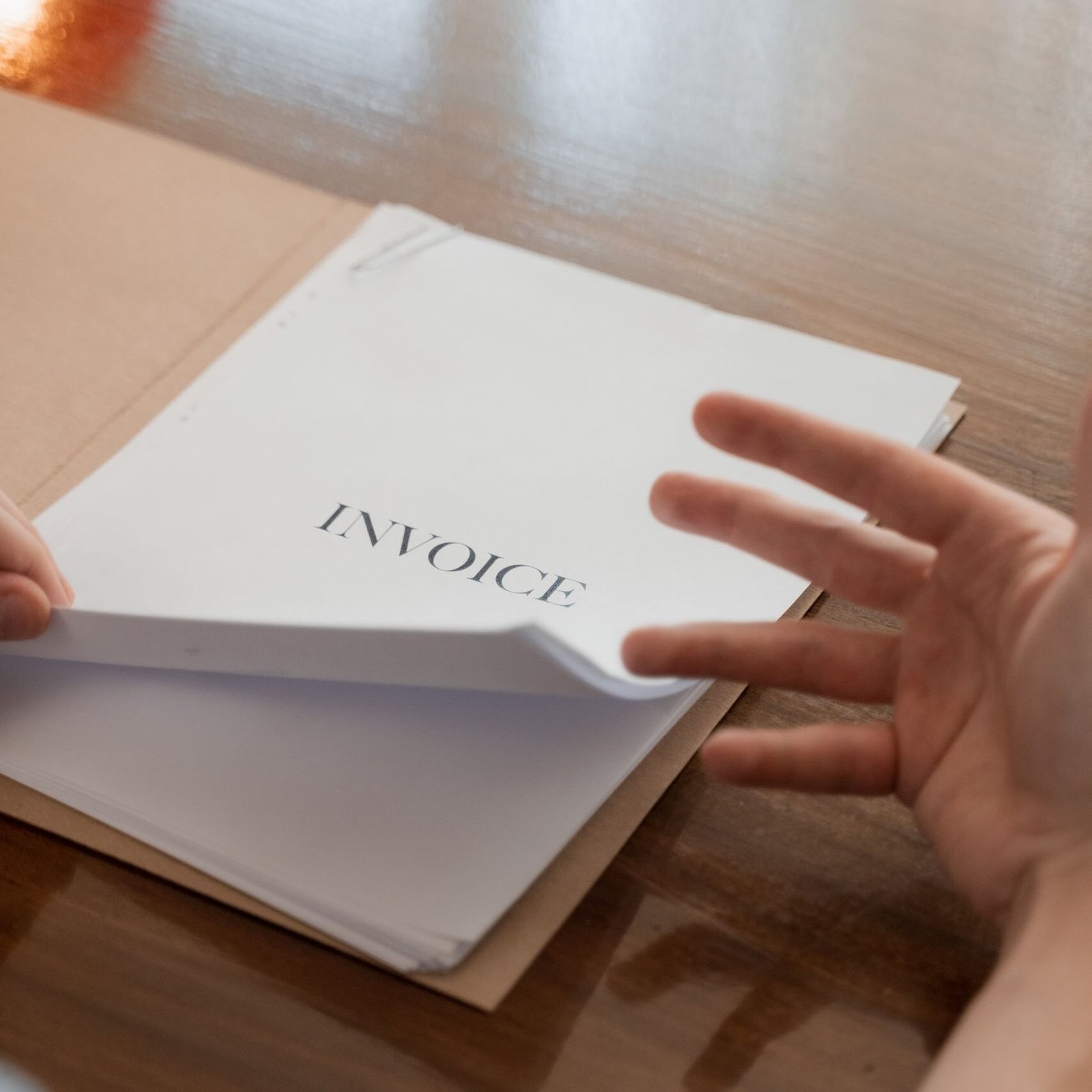 Businessman's hand going through invoices on a table, conveying business management concept.